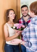 52043549-senior-woman-meeting-smiling-young-family-flowers-at-the-door